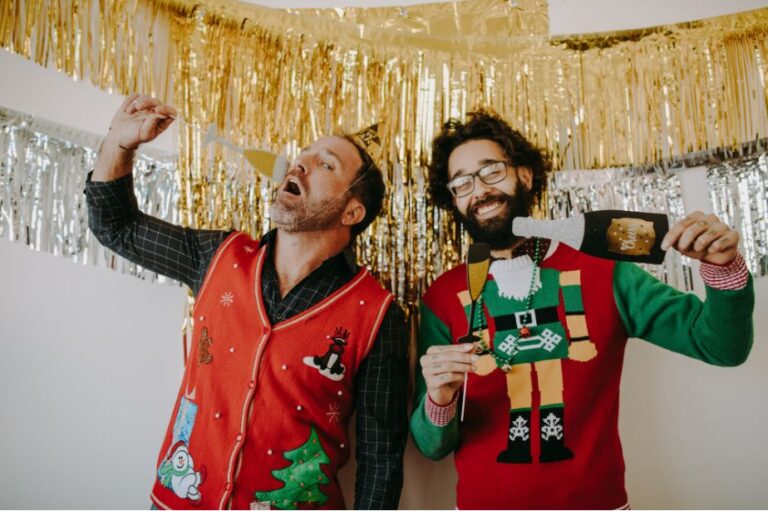 Twee mannen in kersttruien die feestvieren met een notenkraker