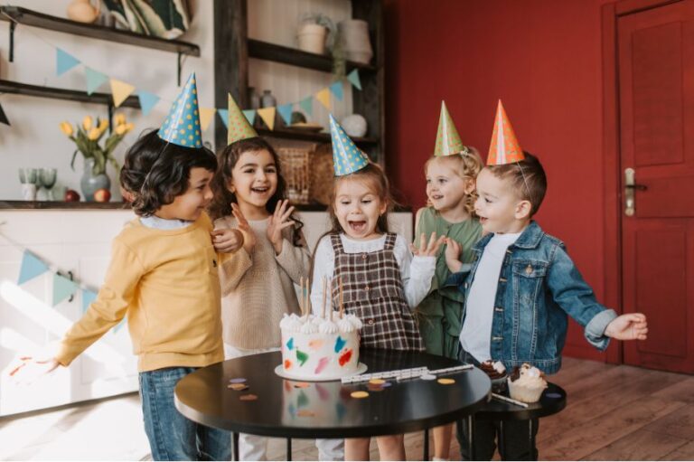 Kinderen met feesthoedjes rond een verjaardagstaart